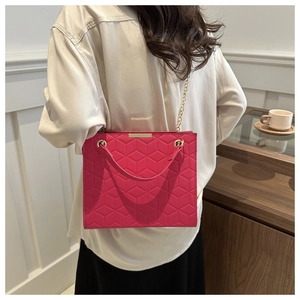 Detail of rose pink crossbody bag featuring geometric hexagonal texture and gold chain