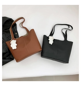 Detail of leather tote bags with lychee grain texture and cute teddy bear charms