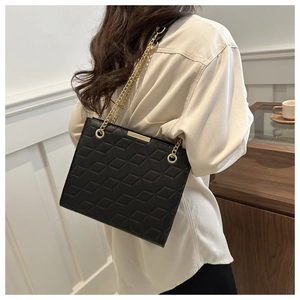 Detail of a black geometric quilted chain shoulder bag with gold metal hardware accents