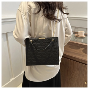 Quilted black chain shoulder bag with geometric patterns and gold hardware on model