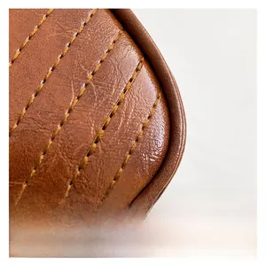 Macro view of brown leather bag with lychee texture and decorative yellow stitching