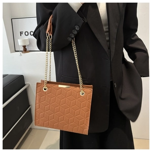 Detail of caramel brown tote bag featuring geometric hexagonal embossing and gold chain
