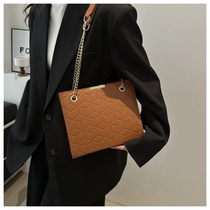 Close-up of caramel shoulder bag featuring geometric hexagonal texture and gold chain