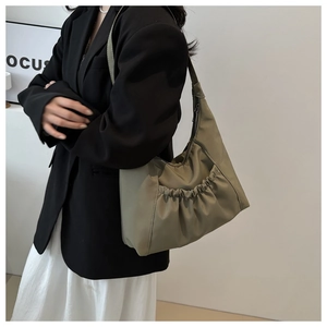 Olive green nylon bucket bag with pleats worn by a model in a minimalist black outfit