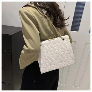 Detail of off-white quilted tote bag with gold chain strap worn by a model