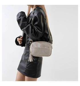 Détail du sac bandoulière gris clair avec sangle tissée colorée et gland en cuir souple
