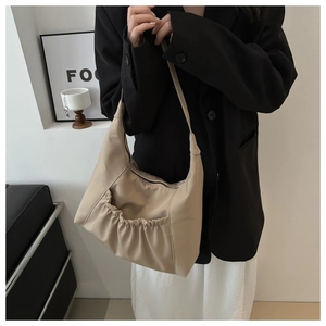 Detail shot of apricot crescent shoulder bag with stylish pleated front pocket design