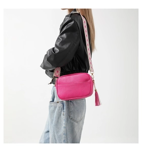 Close-up of magenta camera bag featuring lychee grain leather and colorful woven strap