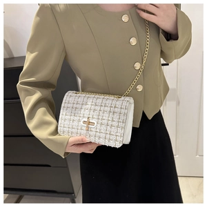 Gros plan du sac bandoulière en tweed crème avec chaîne dorée et fermoir à tourniquet