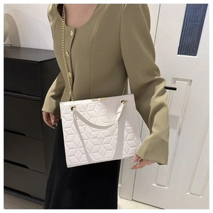Detailed close-up of white quilted handbag with geometric pattern and gold chain strap
