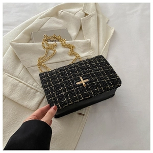 Détail du sac en tweed avec chaîne dorée et fermoir rotatif sur un blazer blanc élégant