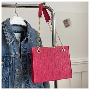 Detail of rose red quilted crossbody bag with golden chain and geometric hex pattern