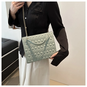 Detailed close-up of mint green quilted tote bag with gold chain strap and modern texture