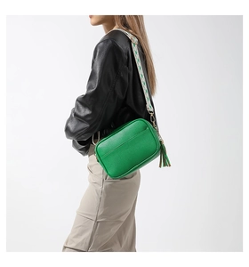Dettaglio borsa a tracolla verde con trama a litchi e tracolla in tessuto colorato