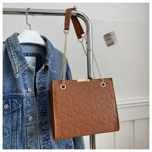 Detail of caramel quilted tote featuring geometric patterns and gold chain strap
