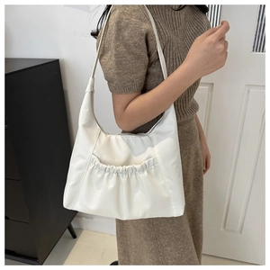 Detail of white pleated nylon crossbody bag showing crescent shape and shoulder strap style