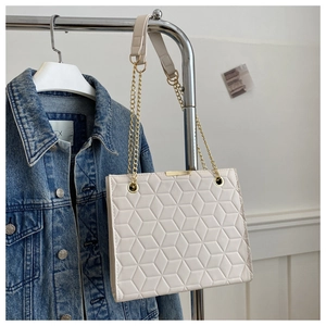 Detail of beige quilted shoulder bag with 3D geometric texture and gold chain strap