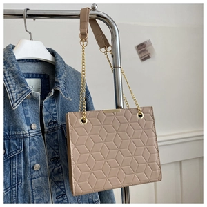 Detail of beige shoulder bag with geometric embossed texture and gold chain strap