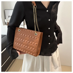 Brown quilted leather chain bag with diamond stitching shown on a model's shoulder