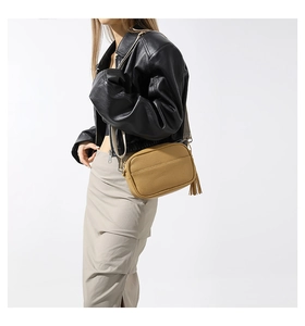 Detail of camel pebbled leather crossbody bag with tassel zipper and gold hardware