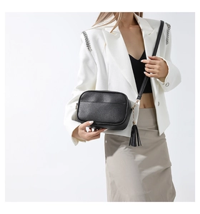 Detail of black pebbled leather camera bag with tassel zipper and golden hardware