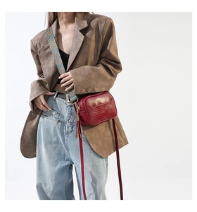 Detail of burgundy PU leather crossbody bag with embroidered strap and tassel accessory