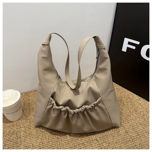 Detail of khaki soft PU bucket bag with pleated pocket on brown textured surface
