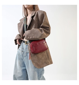 Détail du sac bandoulière matelassé bordeaux avec large sangle ethnique porté par un mannequin