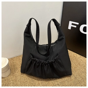Detail of black PU leather tote bag featuring pleated front pocket and top zipper closure