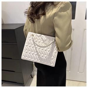 Close-up of quilted tote bag with geometric stitching and elegant gold chain strap
