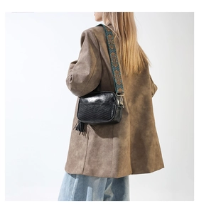 Détail d'un sac photo en cuir noir avec une large bandoulière ethnique colorée