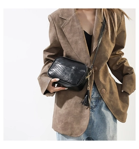 Détails du sac photo bandoulière noir avec matelassage en V et pompon doré sur le zip