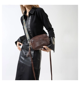 Close-up of brown PU crossbody bag featuring V-stitch patterns and bohemian strap detail