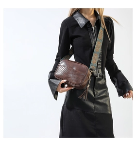 Detail of chevron embossed brown PU leather crossbody bag with ethnic style strap and tassel