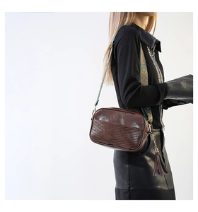 Détail du sac bandoulière marron vintage avec surpiqûres en V et sangle tissée large