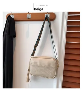 Détail du sac caméra beige avec coutures en V et bandoulière ethnique en jacquard