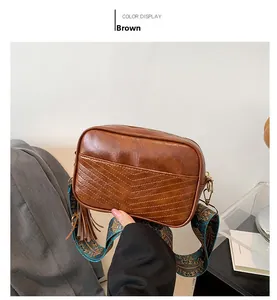 Détail du sac bandoulière marron vintage avec sangle ethnique et pompon décoratif
