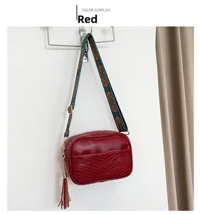 Sac caméra vintage rouge avec large bandoulière ethnique et pompon décoratif élégant