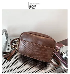 Détail du sac caméra en similicuir marron avec matelassage en V et long gland décoratif