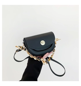 Close-up of black leather saddle bag with gold metal clasp and floral scarf handle wrap