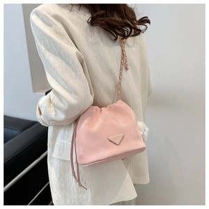 Detail der rosa weichen PU-Beuteltasche mit Goldkette und weißem Plüschball-Anhänger