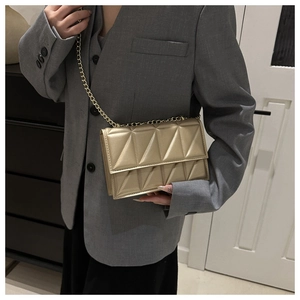 Detailed view of a gold chain strap on a modern quilted metallic handbag with triangle patterns