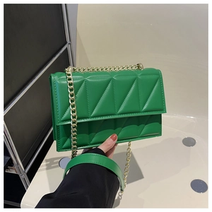 Detail of vibrant green quilted crossbody bag with gold chain strap and stitching