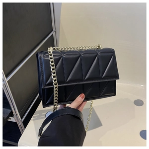 Close-up of black quilted shoulder bag with geometric stitching and gold chain strap