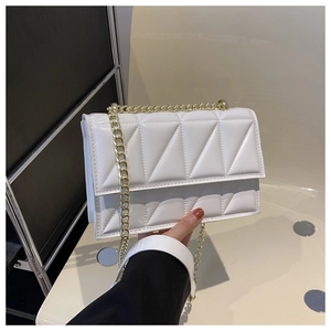Detail of white quilted crossbody bag with gold chain strap and geometric padding