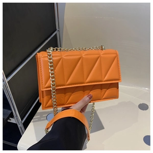 Close-up of vibrant orange crossbody bag with modern triangle quilting and gold chain strap