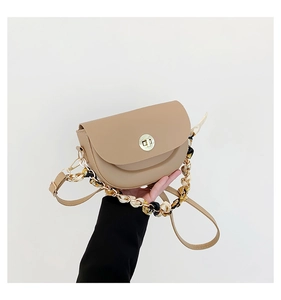Detail of khaki saddle bag with golden clasp and silk scarf wrapped chain strap