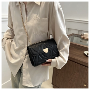 Detail of black heart-quilted shoulder bag with gold heart-shaped metal twist lock