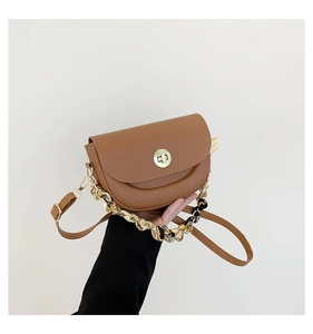 Detail of caramel saddle bag with gold clasp and silk scarf wrapped chain handle