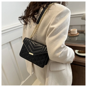 Détail du petit sac bandoulière matelassé noir avec chaîne dorée et fermoir en métal
